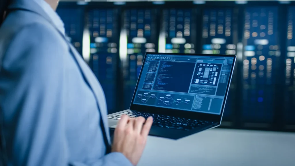 Technician using a laptop to monitor server systems in a data center