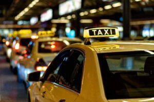 Taxis lined up at night with illuminated taxi signs