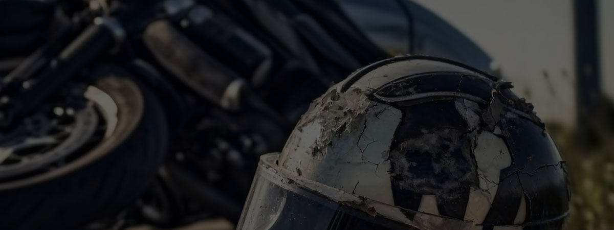 Cracked motorcycle helmet with a motorcycle in the background