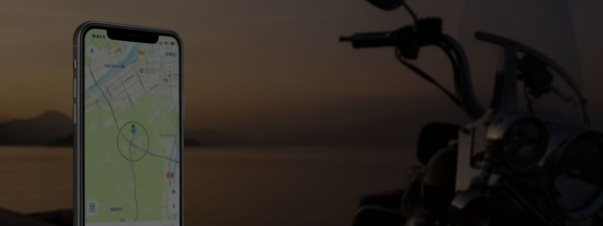 Smartphone displaying a map with a location marker beside a motorcycle at sunset