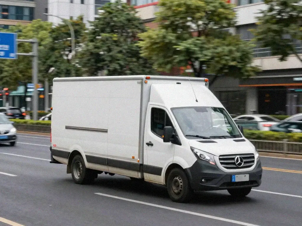 White Mercedes delivery truck driving on a city street