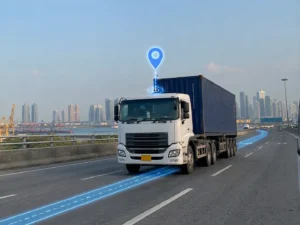 Semi-truck driving on a highway with a glowing location pin and route line, with a city skyline in the background