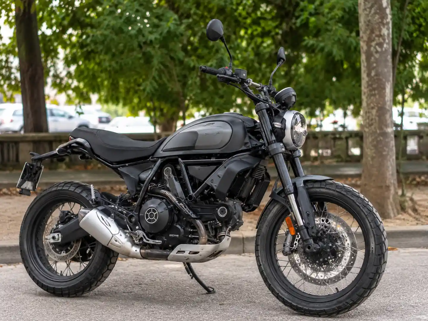 Black motorcycle parked on a street with trees in the background