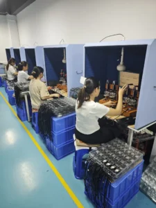 Workers assembling and testing electronic components at factory workstations