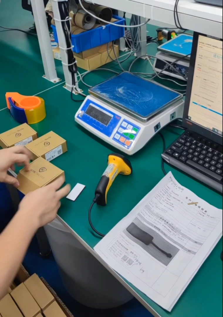 Packing station with a digital scale, barcode scanner, computer, and hands labeling small boxes