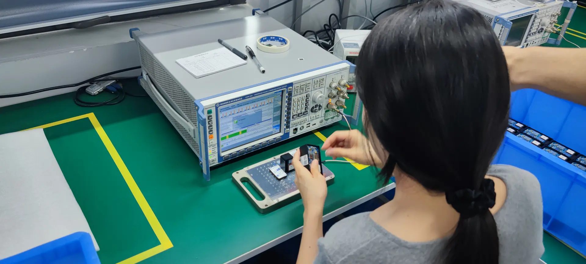 Technician testing a circuit board with lab measurement equipment on a workbench