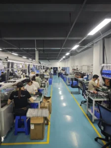 Workers assembling electronics at benches in a factory workspace