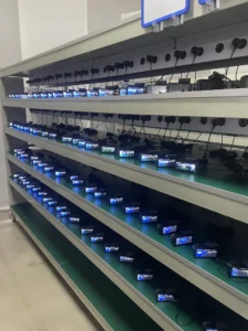 Rows of action cameras charging on multi-tier shelves in a storage rack