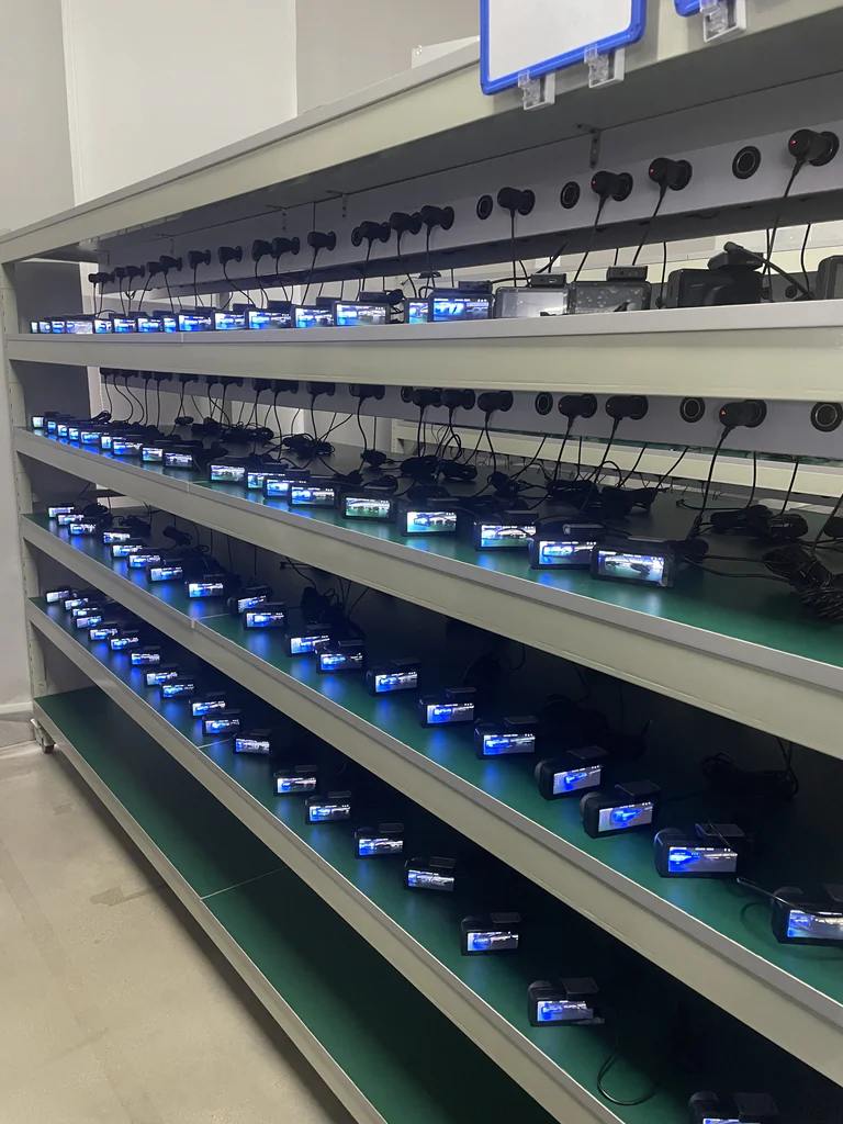 Rows of action cameras charging on multi-tier shelves in a storage rack